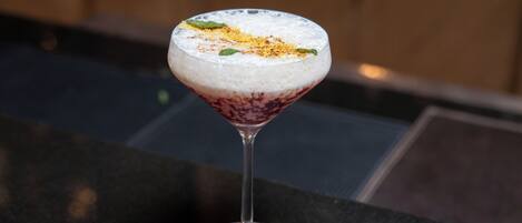 A cocktail in a martini glass on a dark countertop.