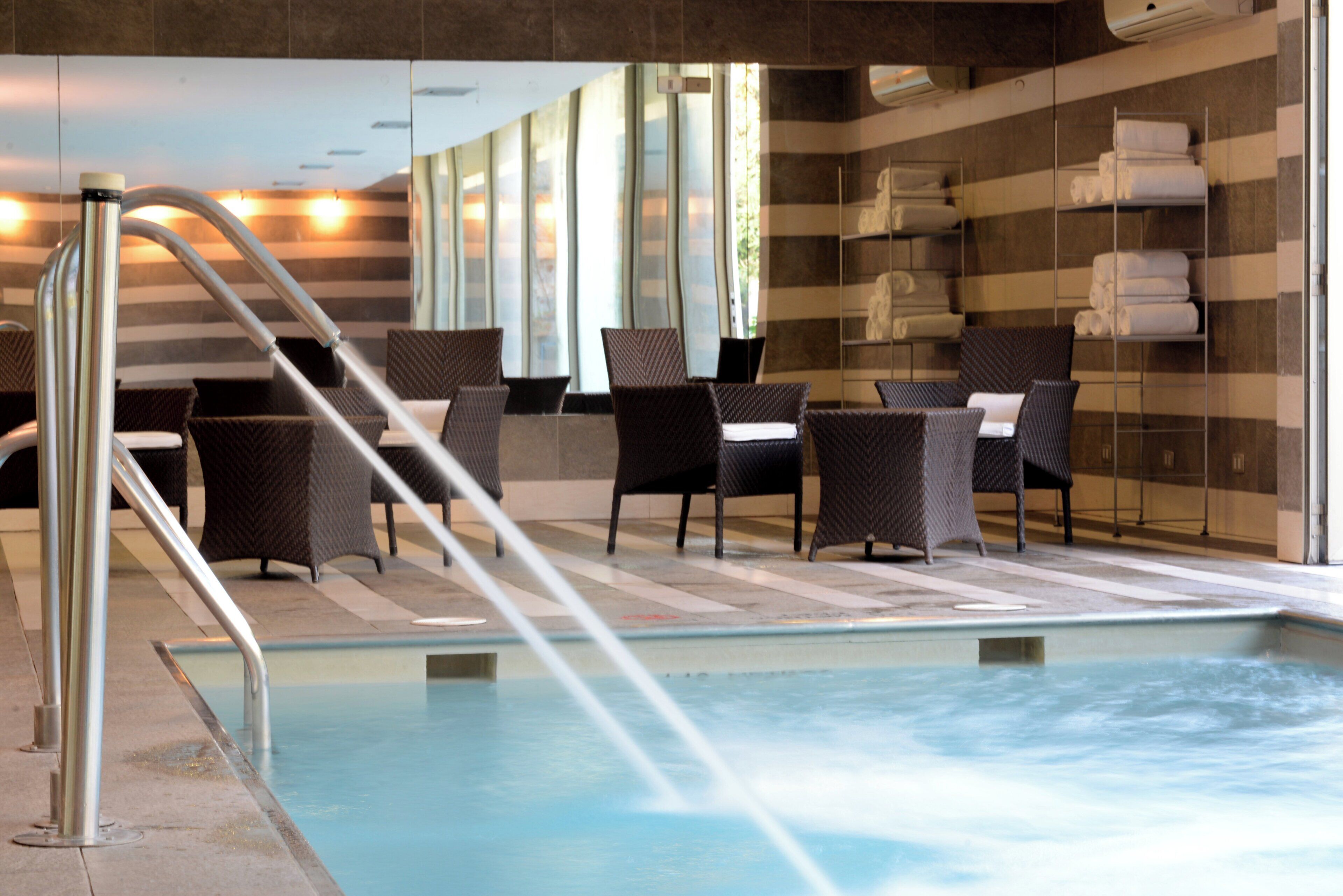 Zona de piscina con sillas y fuente de agua.