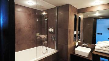 Un baño moderno con ducha de vidrio, una bañera blanca y un lavamanos con lavabo y espejo.