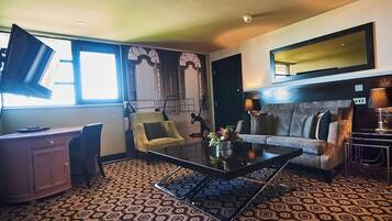 Um quarto com uma escrivaninha, duas poltronas, um sofá, uma mesa de centro e um tapete estampado.