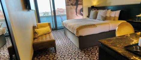 A hotel room with a bed, a desk, a chair, and a large window.