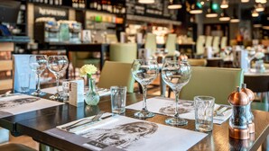A restaurant interior with tables set for dining, featuring clear glassware and menus. - The Vincent Hotel (Southport)