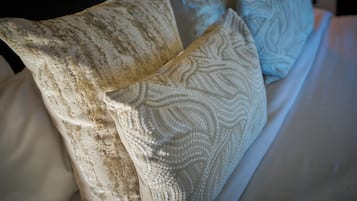 Una cama con varios almohadones, algunos con textura y otros lisos.