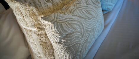 A bed with multiple pillows, some with a textured pattern and others with a smooth surface.