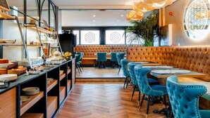 Un restaurante moderno con una barra larga, sillas tapizadas en azul y una zona de asientos con banco acolchado.