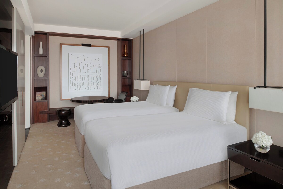 Ein Hotelzimmer mit einem großen Bett, Nachttischen, einem Fernseher und einem Wanddekor.