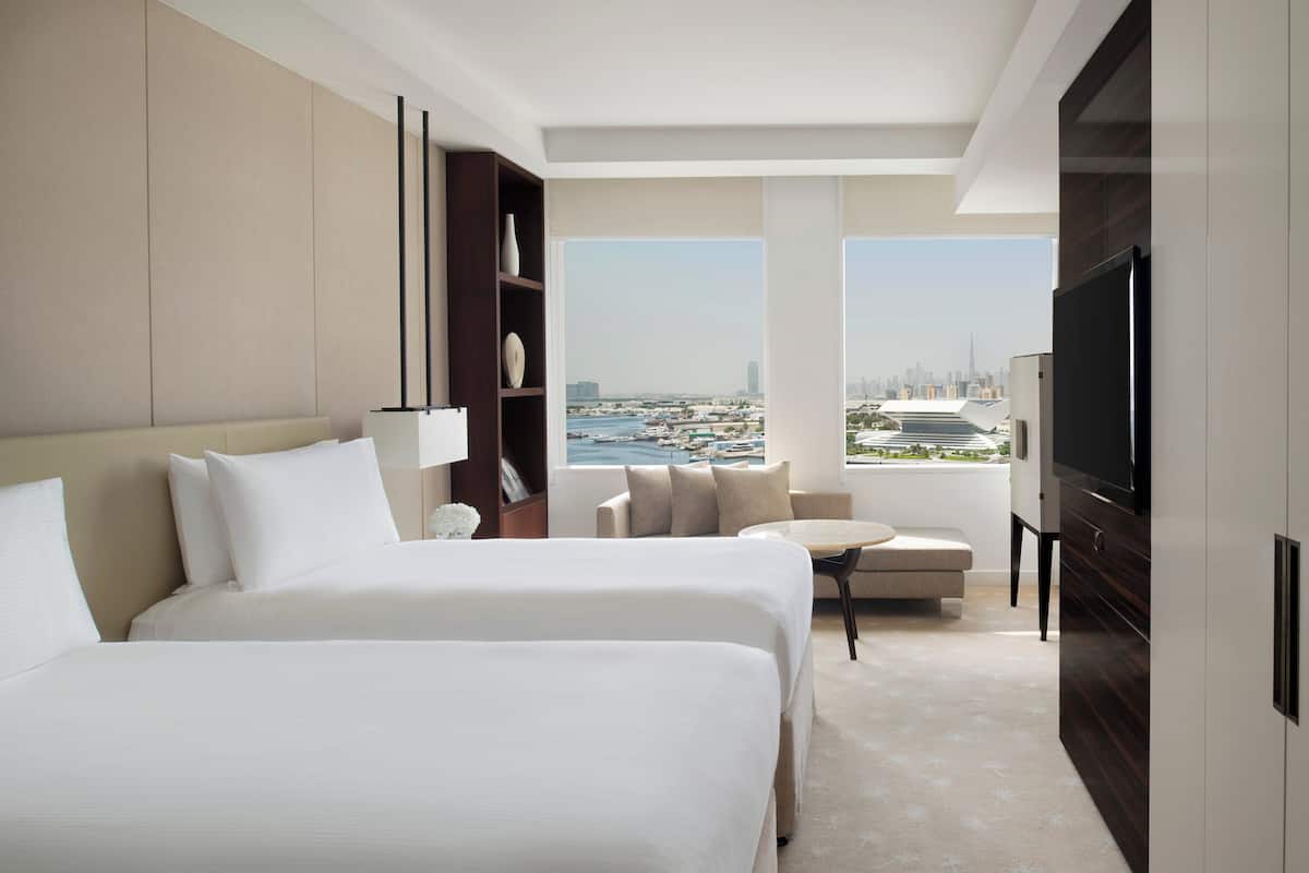 Una habitación de hotel moderna con dos camas, televisión y vista a la ciudad.