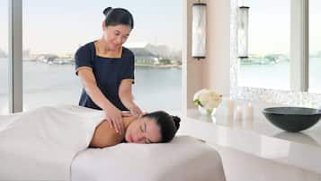 Experience a serene spa setting with a view of the water and cityscape, featuring a massage table and a skilled therapist.