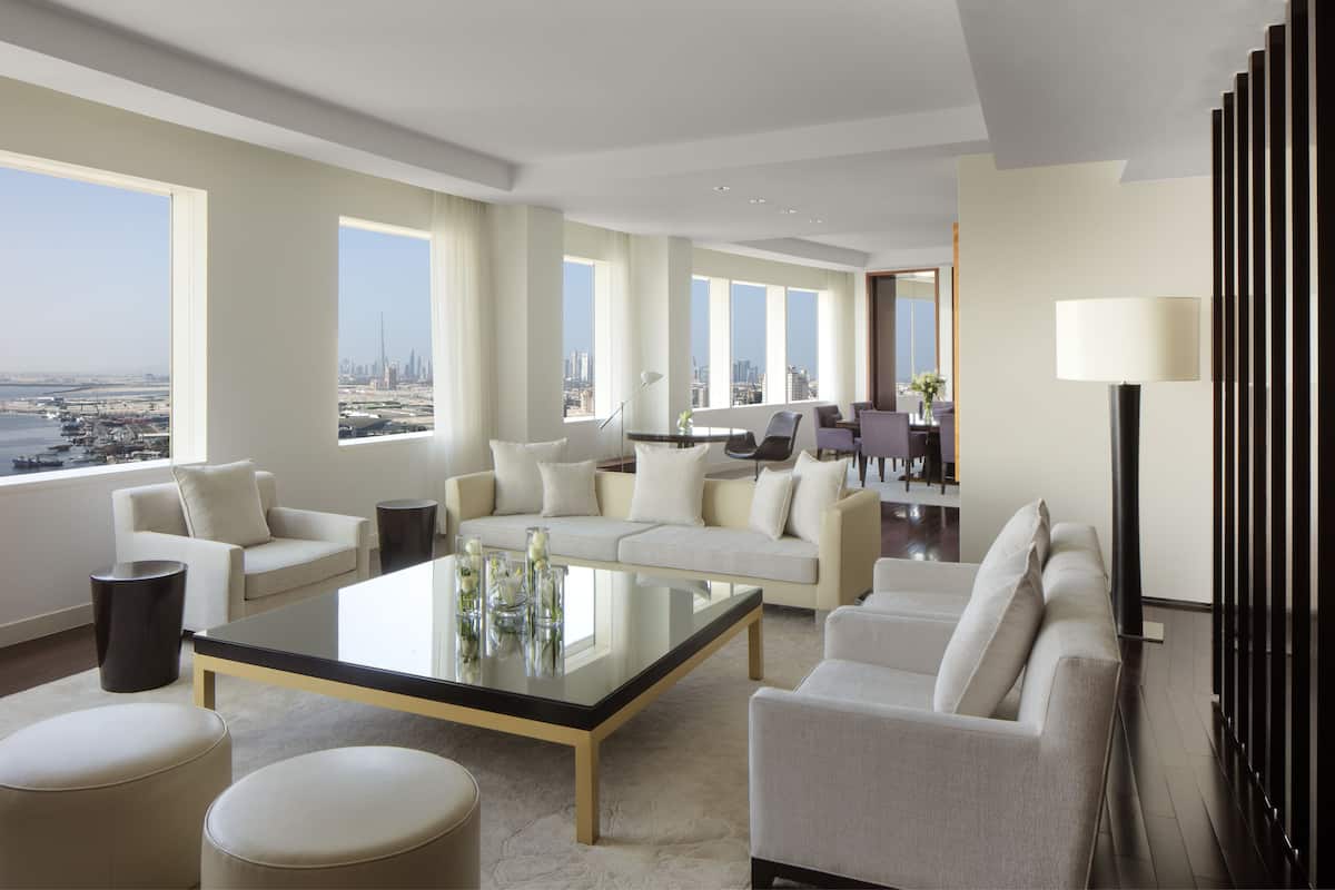 Una sala de estar moderna con una mesa de centro de vidrio, dos sofás y vistas a un paisaje urbano.