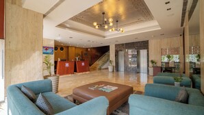 A spacious lobby with a high ceiling, a reception desk, and a staircase leading to upper floors. - Royal Orchid Central Jaipur (Jaipur)