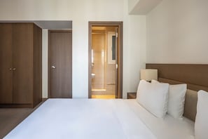 A hotel room with a large bed, wooden wardrobe, and a bathroom visible through an open door. - Amalia Hotel Athens (Athens)