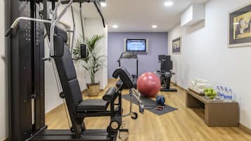 Ein Fitnessraum mit Trainingsgeräten, Laufband, Ergometer und einem Fernseher.