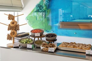 Un bufé con diversos alimentos, incluyendo pan, verduras y salsas.