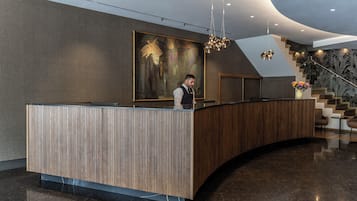 Un mostrador de recepción de diseño moderno, un cuadro abstracto de gran tamaño en la pared y una escalera con un revestimiento decorativo.