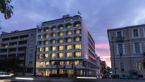 Un hôtel à plusieurs étages, doté de balcons, d’une entrée bien visible et donnant sur la rue, avec des feux de signalisation.