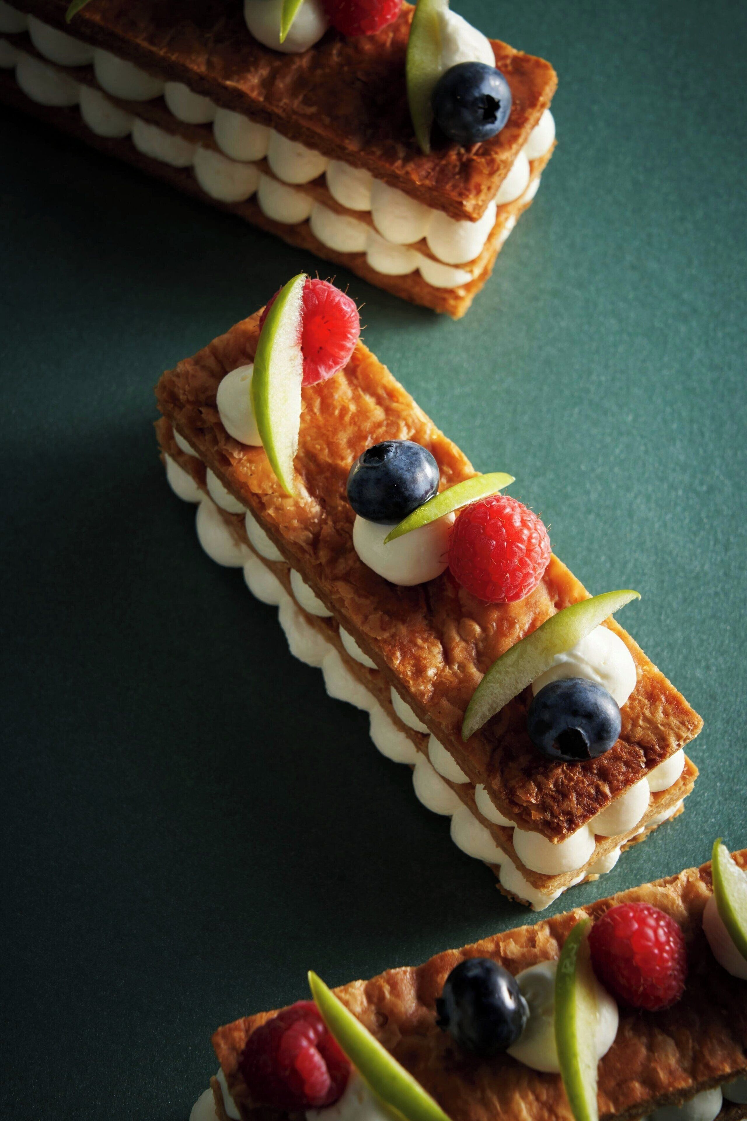 Un postre con fruta y crema sobre una superficie oscura.