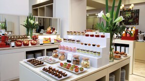 A buffet with various food items and desserts displayed on shelves and plates. - NH Collection Buenos Aires Lancaster (Buenos Aires)