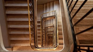 A spiral staircase with wooden steps and a metal railing. - NH Collection Buenos Aires Lancaster (Buenos Aires)