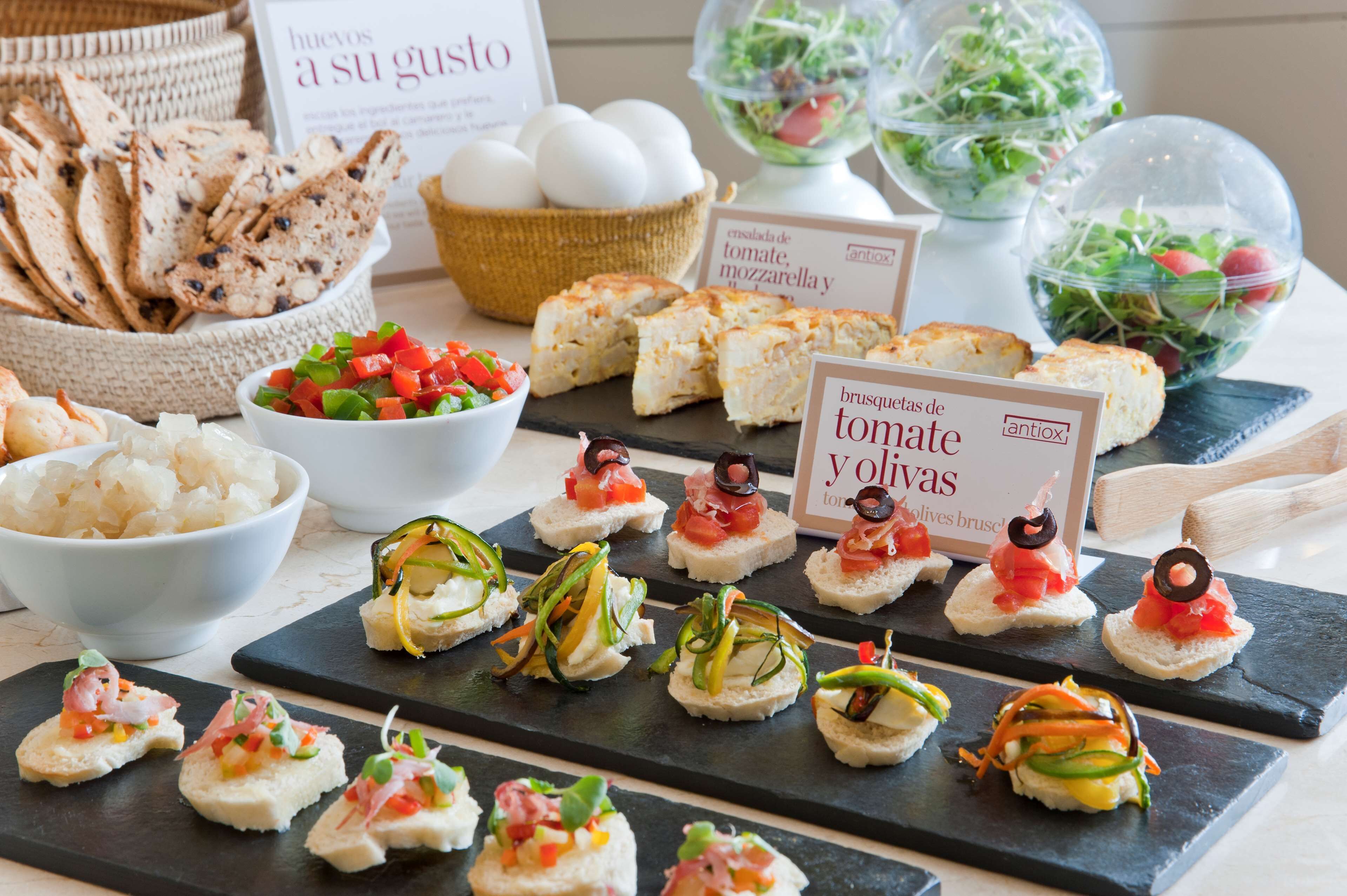 Diversos aperitivos, como bruschetta y canapés, dispuestos sobre tablas de pizarra.