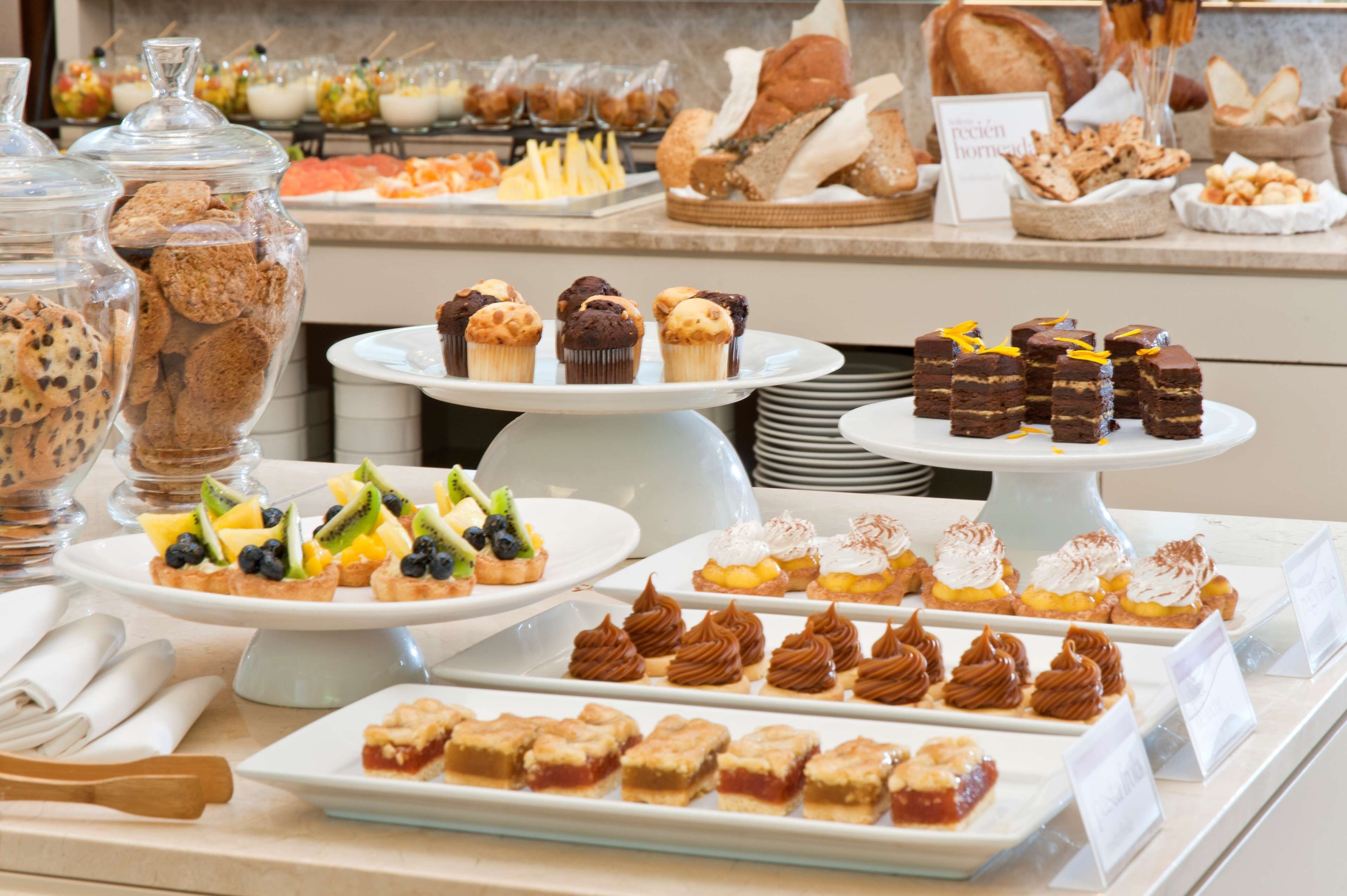 A buffet with various desserts and pastries, including cupcakes, tarts, and brownies.