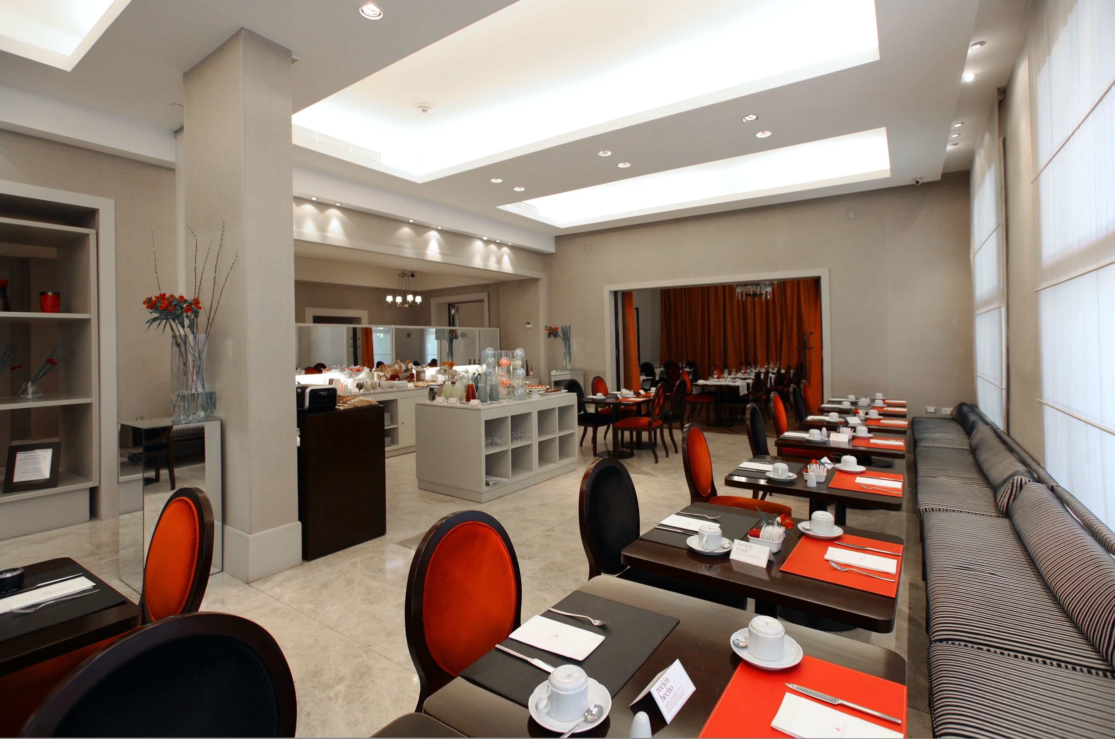 A modern dining area with multiple tables and chairs, a central counter, and a seating area with a sofa.