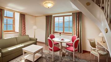 Une pièce comprenant un canapé, une table à manger avec des chaises, une lampe et une vue sur la mer grâce à de grandes fenêtres.