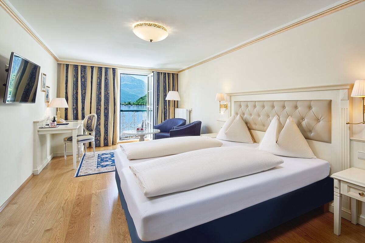 Une chambre d’hôtel avec un grand lit, un bureau, une chaise, une télévision et une vue sur un lac.