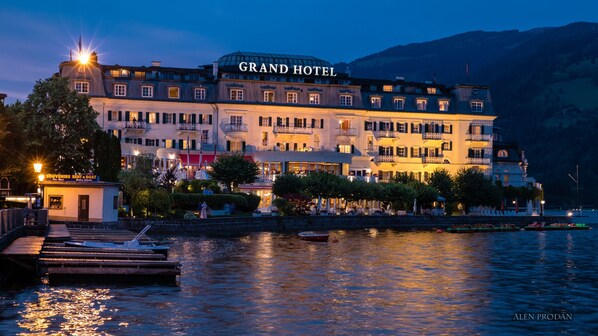 A grand hotel with multiple balconies, a dock with boats, and a waterfront view. - Grand Hotel Zell Am See (Zell am See)