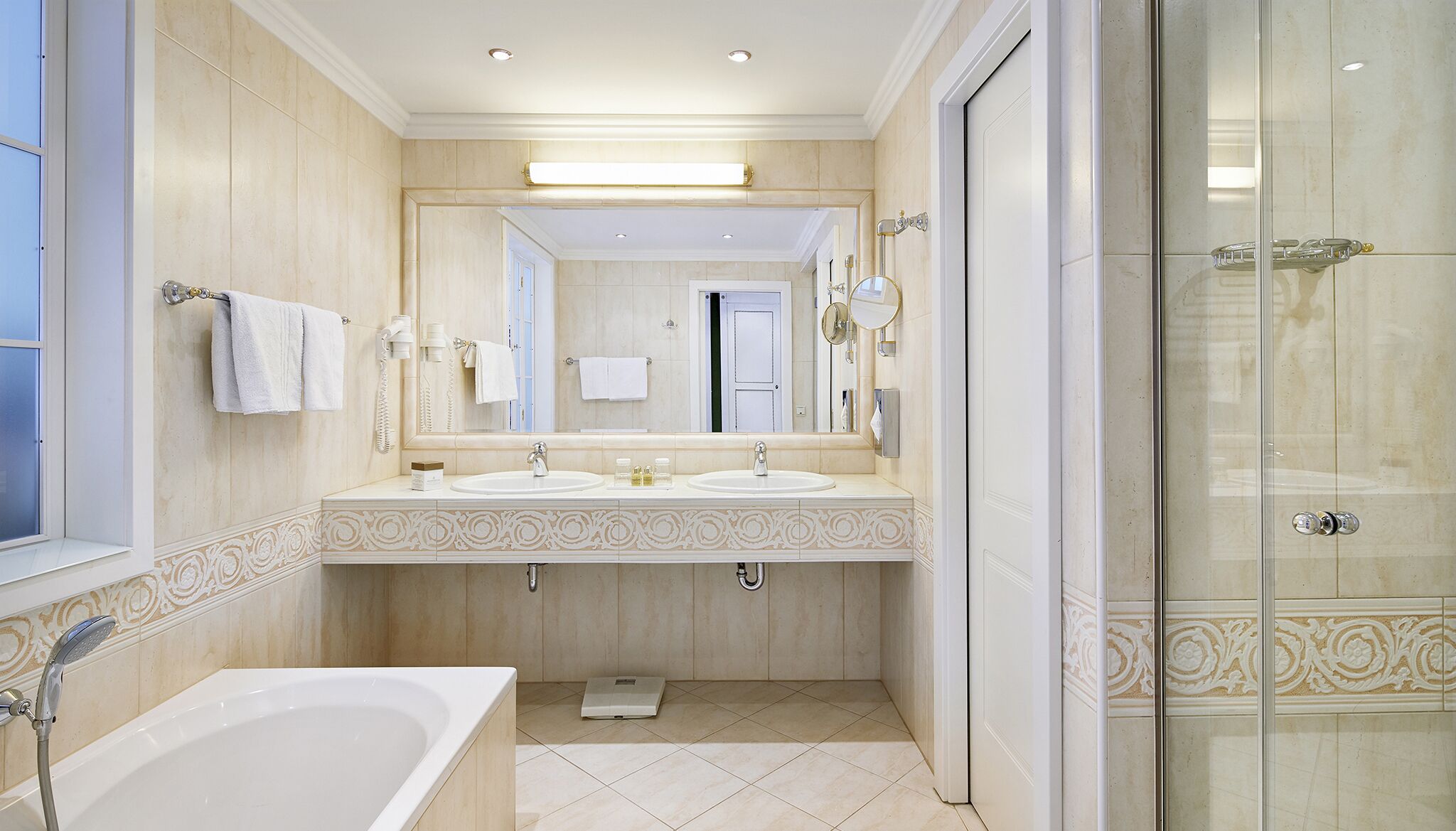 A modern bathroom with two sinks, a bathtub, a shower, and a scale.