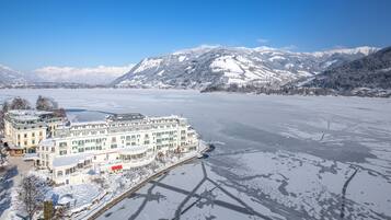 A large hotel with multiple buildings, a waterfront, and snow-covered mountains in the background.