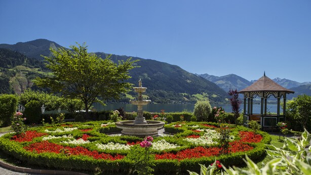 Un jardín con una fuente, un pabellón y montañas al fondo.