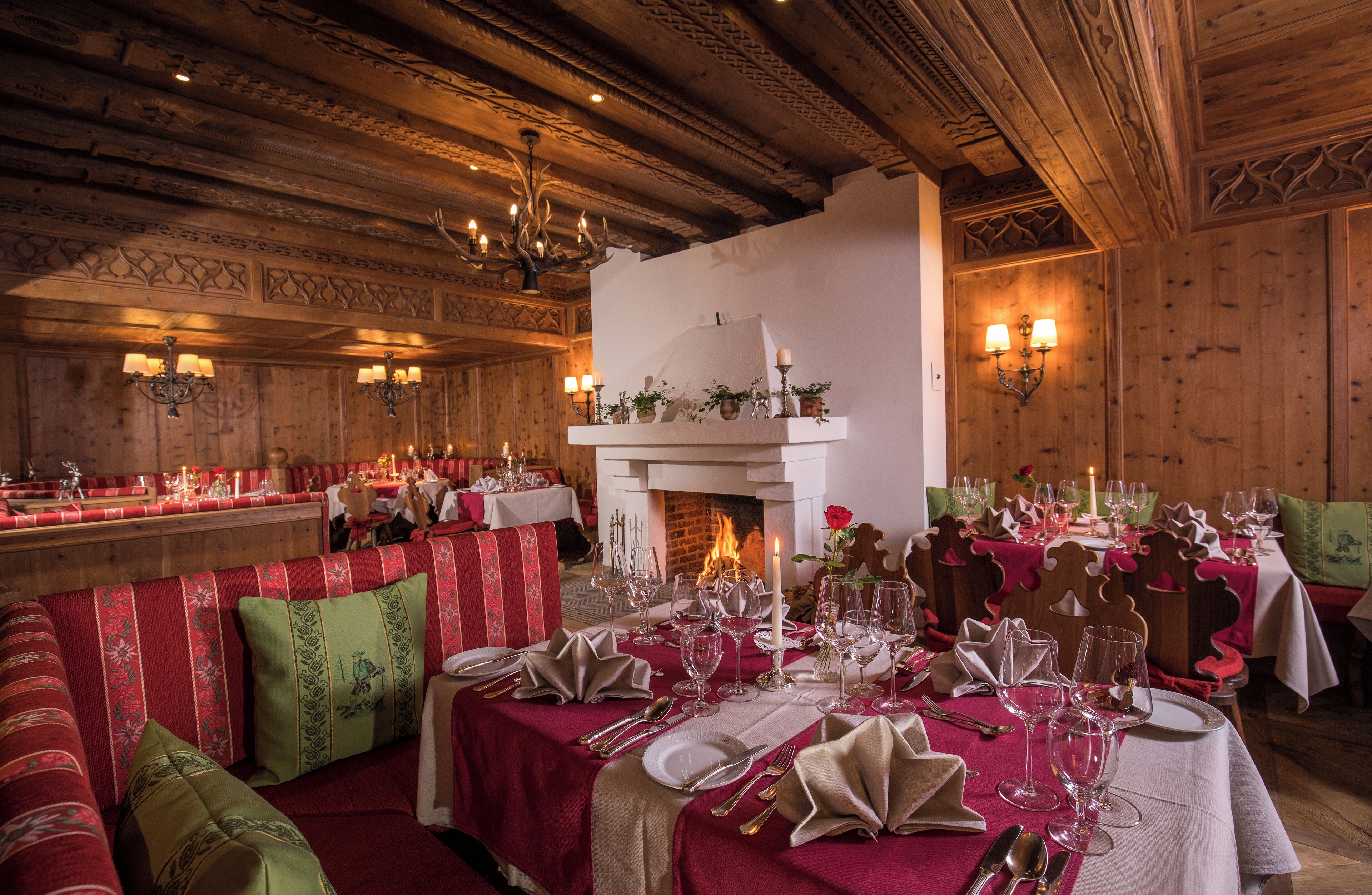 A restaurant with wooden interiors, multiple dining tables set for guests, and a fireplace.