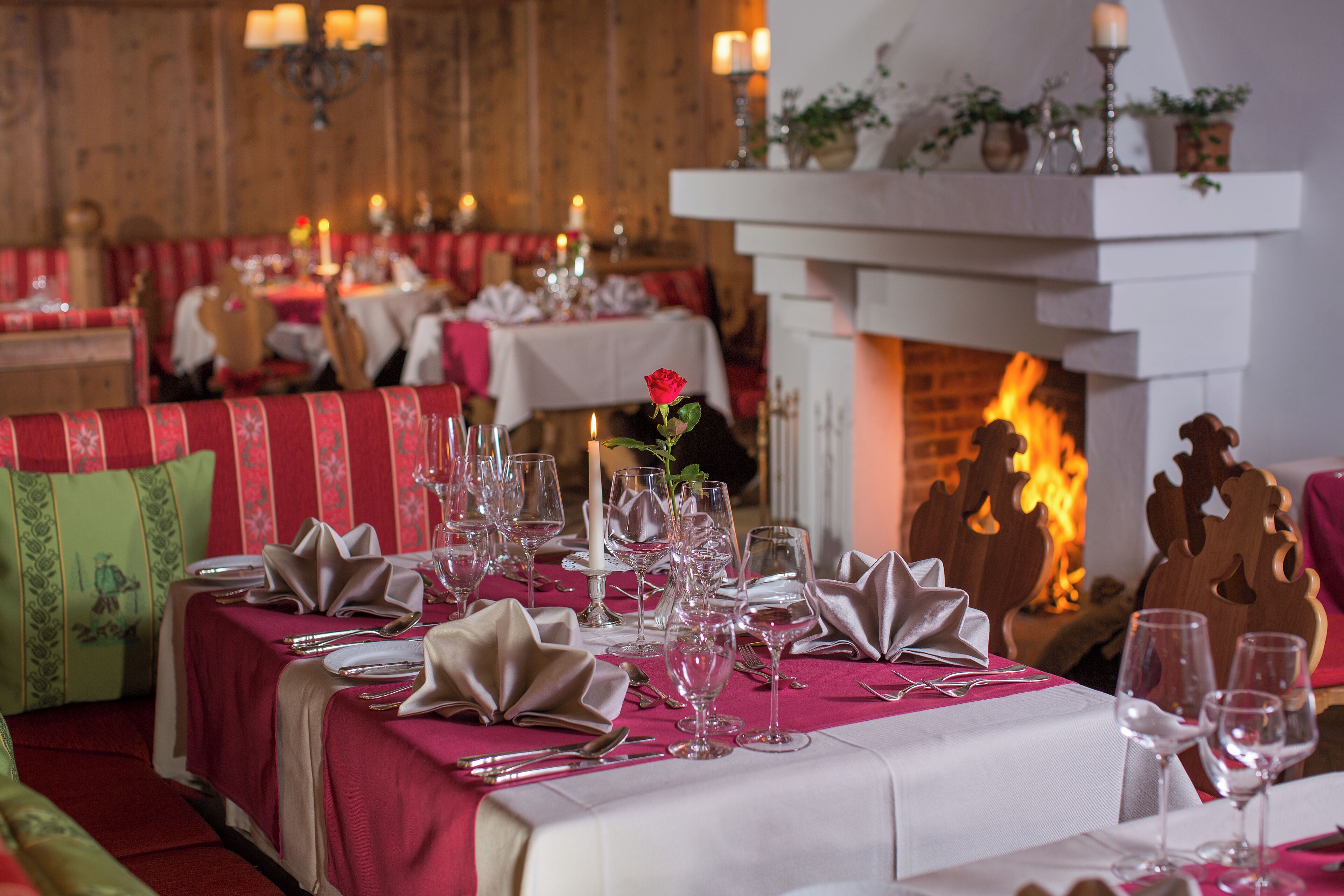 Un comedor con mesas dispuestas para una comida, una chimenea al fondo y un ambiente acogedor.