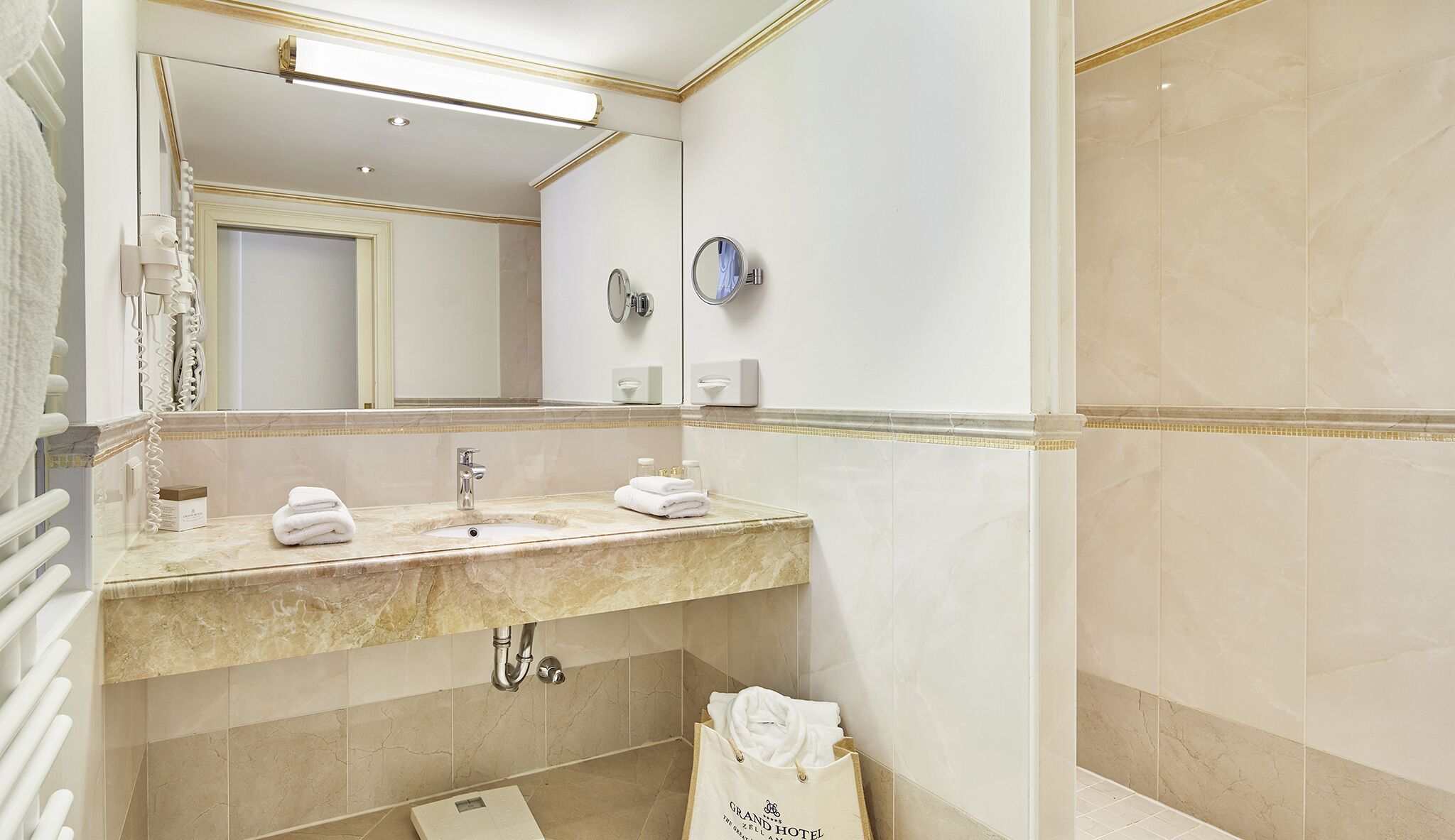 A bathroom with a marble sink, a large mirror, a towel rack, and a shower area.