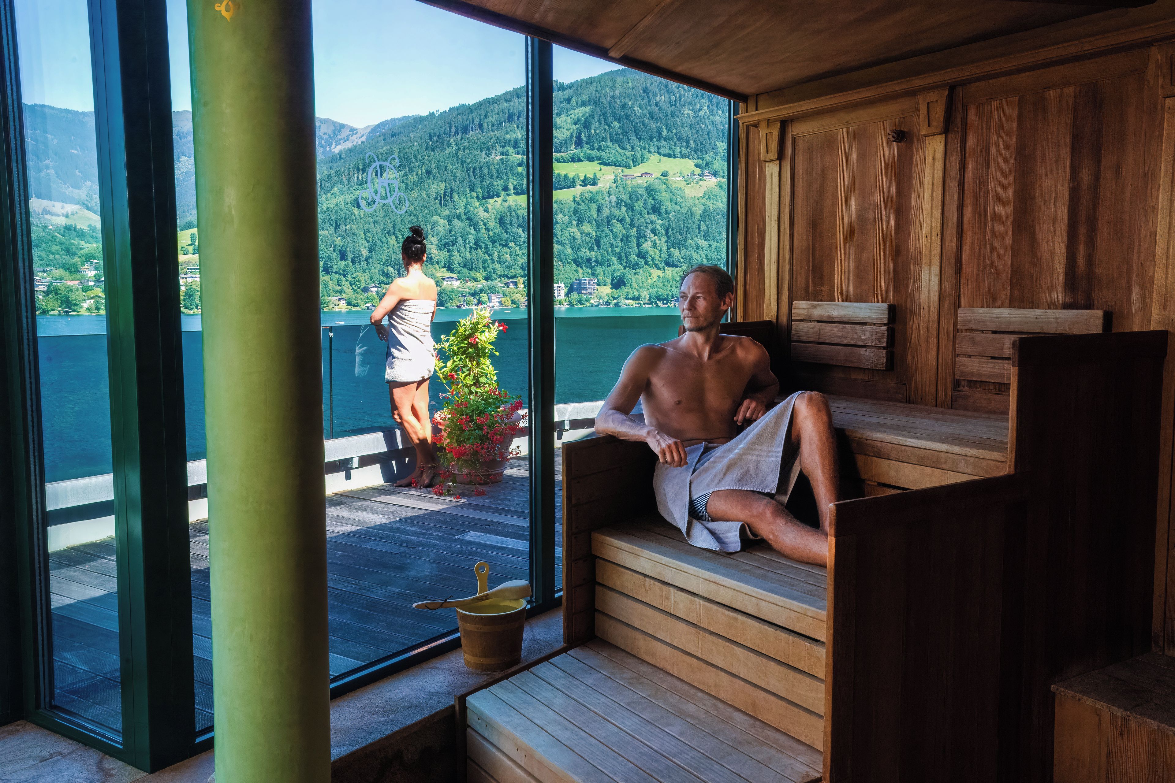 Una sauna con bancos de madera y vistas a un lago y montañas.