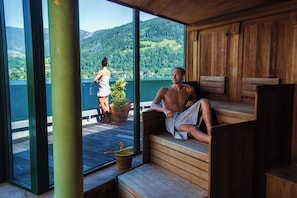 Uma sauna com bancos de madeira e vista para um lago e montanhas.