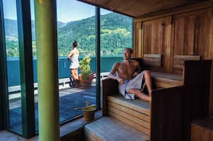 Una sauna con bancos de madera y vistas a un lago y montañas.
