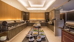 A modern hotel dining area with a long buffet table, wooden paneling, and a skylight ceiling. - Royal Biz Taipei (Taipei)