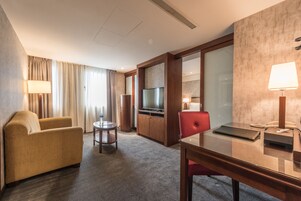Hotelkamer met een bank, een kleintje tafeltje, een bureau met stoel, een televisie en een minibar.