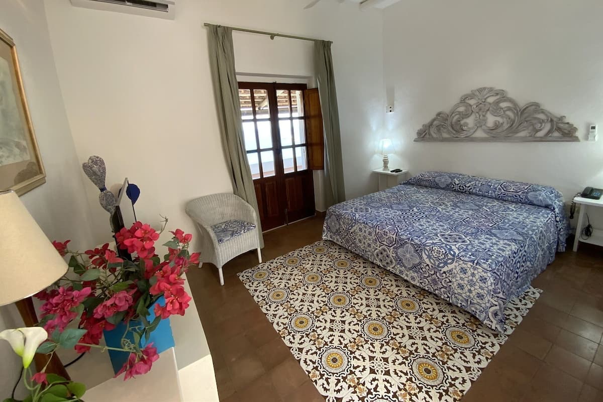 Un dormitorio con cama, una silla, una lámpara y un adorno en la pared.