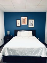 Una habitación de hotel con una cama grande, una mesita de noche y tres cuadros en la pared.