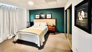 A hotel room with a bed, a nightstand, a framed picture, and a window with curtains. - S.J. Suites Hotel (San Juan)