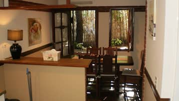 Un comedor con una mesa y sillas de madera, un jarrón con flores y una lámpara sobre una encimera.