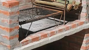 Ein gemauerter Grill für den Außenbereich mit einem Metallrost und Holz als Brennmaterial.