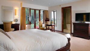 A spacious bedroom with a large bed, a television, a desk with a chair, and a view of the outdoors through large windows. - Garstang Country Hotel & Golf, Sure Hotel Collection (Preston)