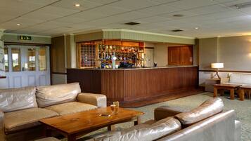 A bar area with a counter, various bottles, and a seating area with sofas and a coffee table.