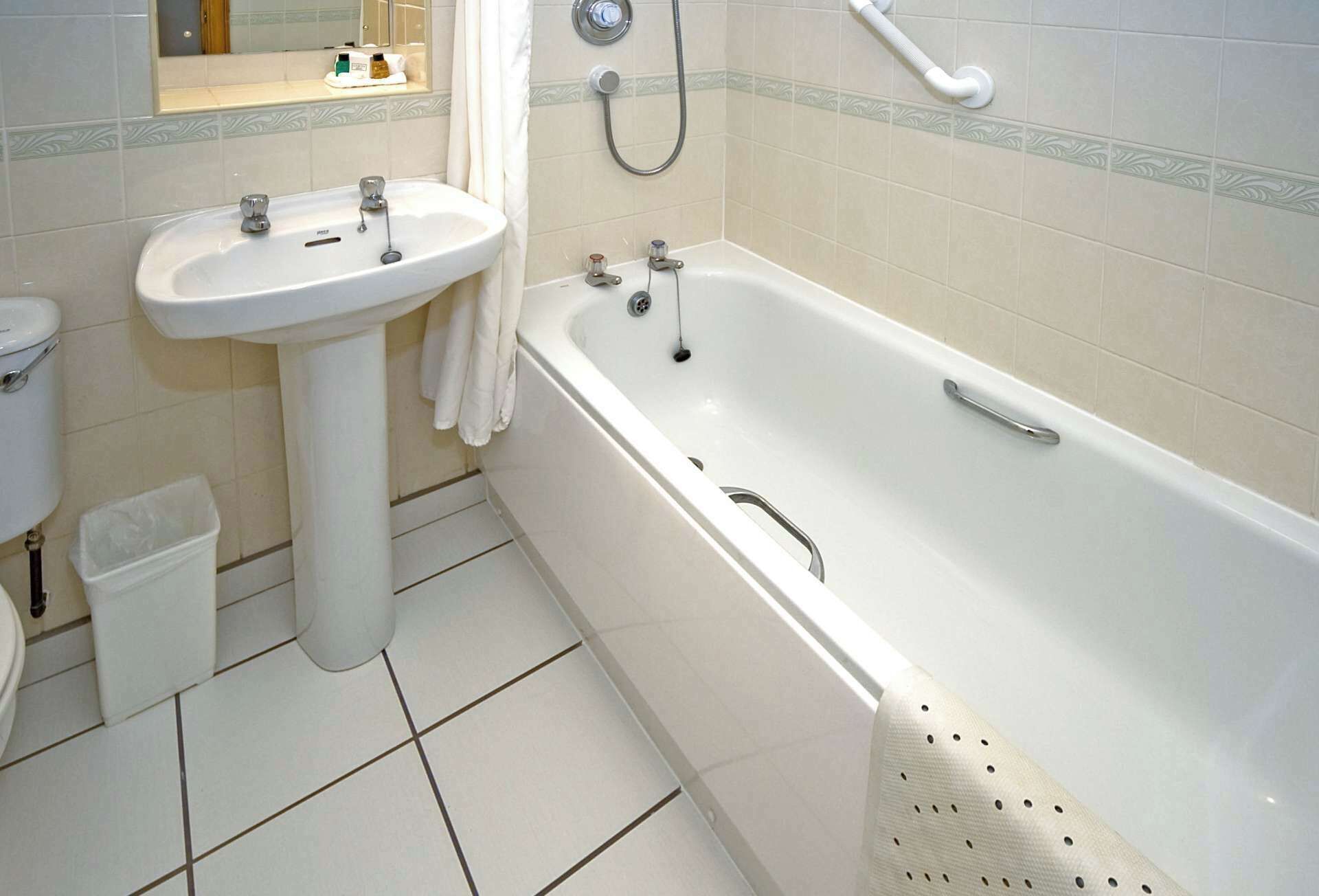 Un baño con lavamanos, inodoro y bañera blancos.