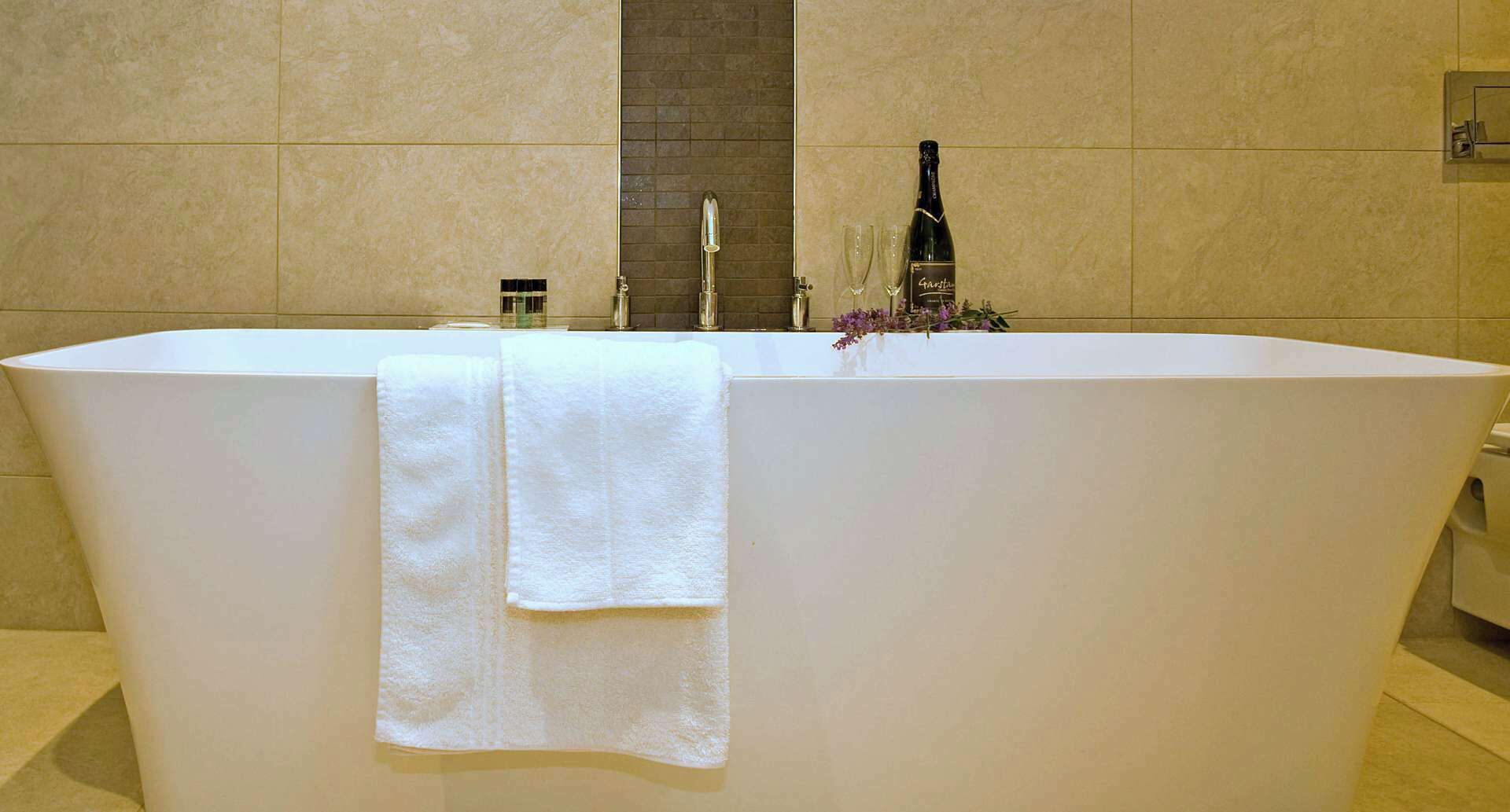 A large, rectangular bathtub with a white towel draped over it.