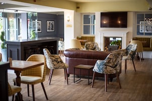 Un interior moderno con un sofá de cuero marrón, sillas estampadas, una mesa de madera y una chimenea.