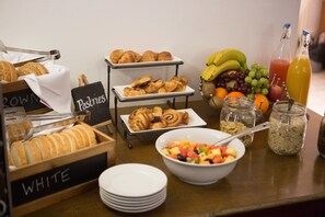 Ein Frühstücksbuffet mit Gebäck, Früchten und Getränken.